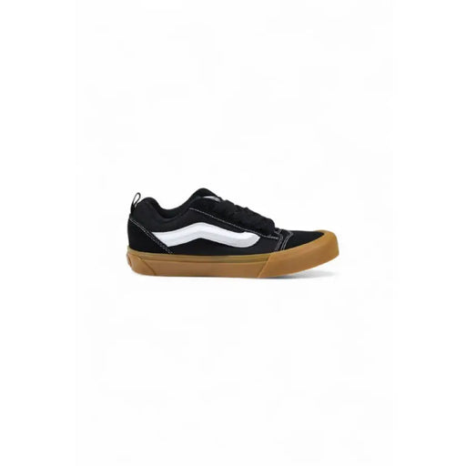Black and white Vans sneaker with a brown sole displayed in the product image
