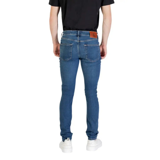 Blue denim skinny jeans paired with white sneakers for men on display