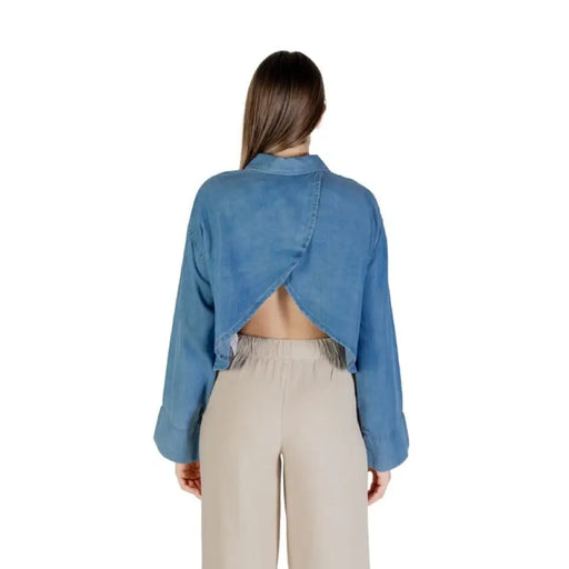 Blue open-back denim cropped shirt paired with beige pants for a stylish look