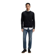 Pull ras du cou Boss Jeans noir pour homme, avec poignets et ourlet côtelés, porté sur une chemise rayée à col, par un mannequin.