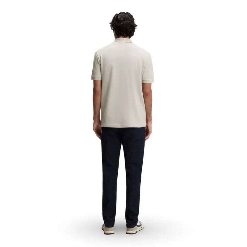 Un homme portant un polo Boss pour homme, gris émeraude, en coton, à col zippé, manches courtes, col classique beige clair et coutures apparentes.