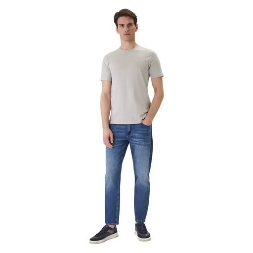 A man wearing a boss men t shirt grey tales round neck cotton short sleeve in light gray with blue jeans