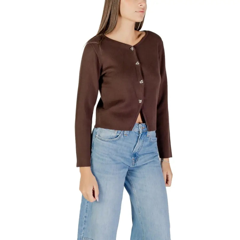 Woman wearing a brown long V neck buttoned cardigan and light wash wide-leg jeans