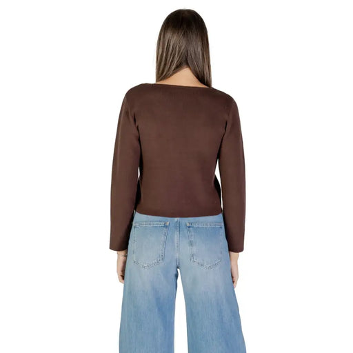 Women wearing a brown long-sleeved V-neck buttoned cardigan with wide-leg blue jeans