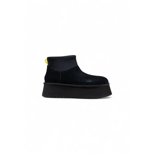Black suede UGG boot with thick platform sole and yellow pull tab