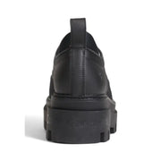 Calvin Klein black leather slip-on women’s shoe with chunky rubber sole and embossed logo on heel back side view