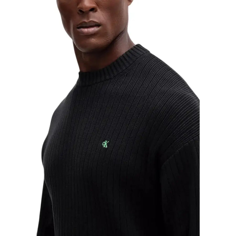Black ribbed sweater with green logo, likely from a popular brand.