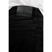 Black calvin klein jeans label with embossed ck logo on dark denim fabric of black cotton stretch shorts for men back side