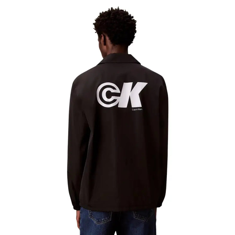 Vue arrière d'une veste de coach Calvin Klein noire avec logo CK blanc audacieux, style blazer classique en polyester.
