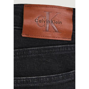 Jean slim en denim de coton noir pour homme, dévoilant l'arrière avec un empiècement en cuir beige orné du logo Calvin Klein
