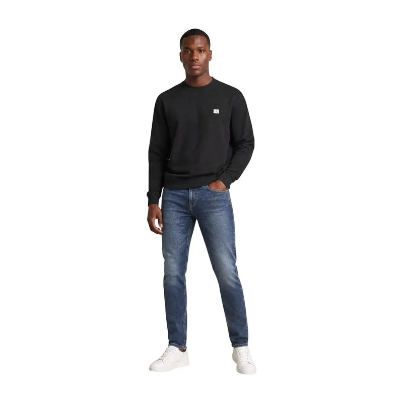 Calvin Klein Jeans Sweat-shirt noir à manches longues et col rond pour homme, en coton, avec un petit logo blanc sur la poitrine gauche.