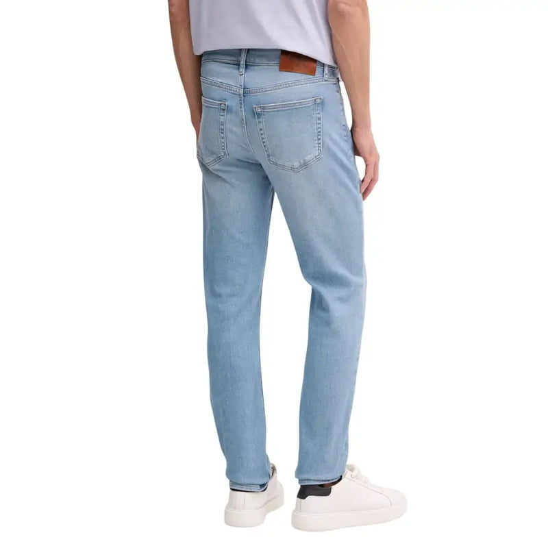 Jean Calvin Klein pour homme, en denim de coton bleu clair, coupe droite classique et empiècement en cuir marron.