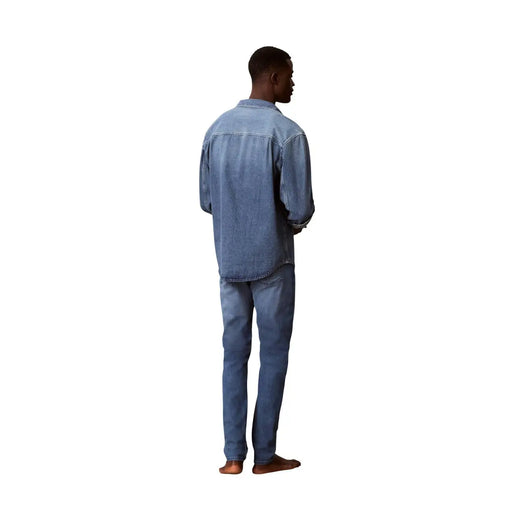 A man wearing calvin klein jeans men blue cotton denim jeans slim fit and a matching light-wash denim shirt