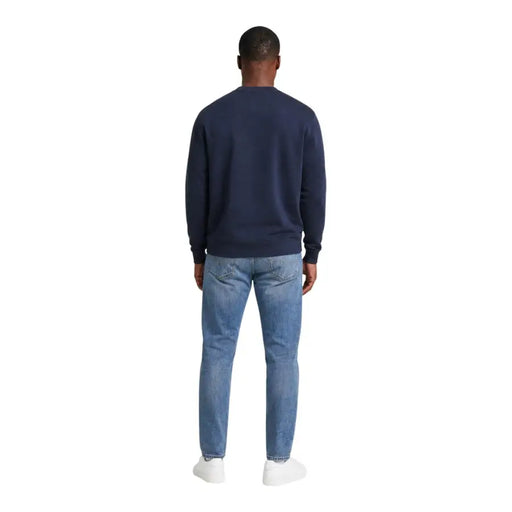 Sweat-shirt Calvin Klein Jeans pour homme, bleu coton, col rond, porté avec un jean en denim clair pour un look décontracté.
