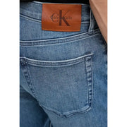 Vue arrière d'un jean en denim de coton bleu pour homme avec une poche zippée et des empiècements en cuir marron Calvin Klein écusson de marque
