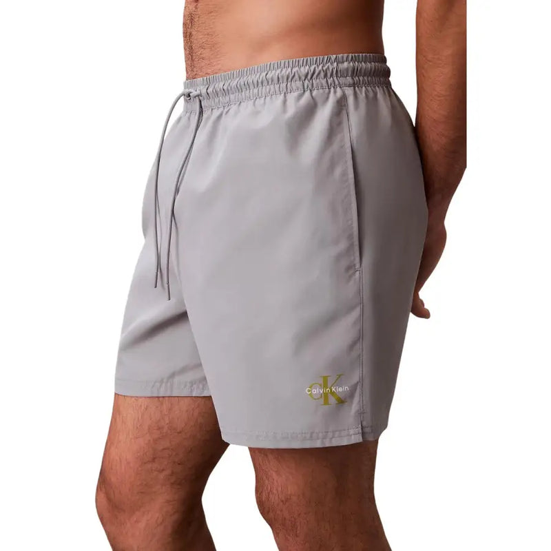 Gray Calvin Klein Jeans men swimwear swim trunks with subtle gold logo on lower leg for beach and pool use