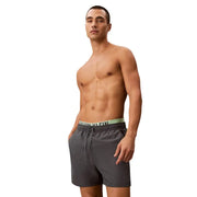 Dark gray Calvin Klein Jeans men swimwear trunks with light green waistband and black logo lettering