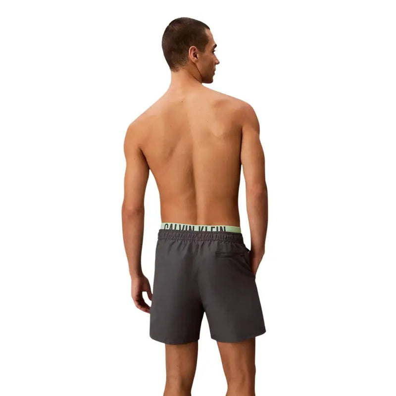 Dark gray calvin klein jeans men swimwear trunks with light green waistband and logo for swimming and beachwear
