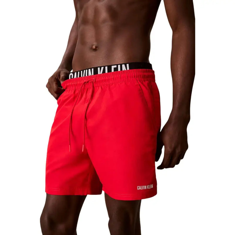 Bright red Calvin Klein Jeans men swimwear trunks with black waistband and white branding featuring matching drawstrings