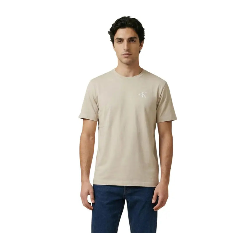 Beige Calvin Klein Jeans hommes t-shirt avec un logo blanc discret sur la poitrine gauche, tissu en coton décontracté
