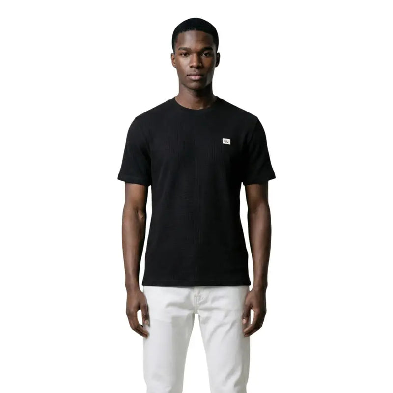 Noir Calvin Klein Jeans hommes t-shirt avec un petit logo blanc sur la poitrine gauche, confectionné en tissu de coton doux