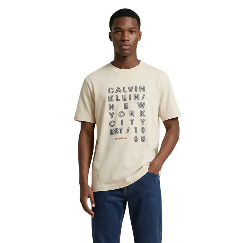T-shirt homme Calvin Klein Jeans couleur crème, en coton, avec imprimé texte noir superposé en gras et logo de la marque en rouge plus petit.