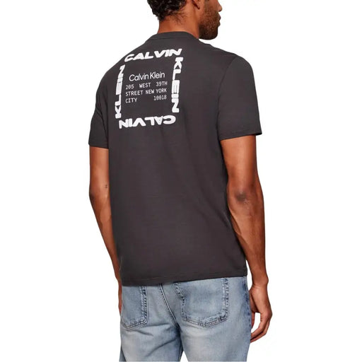 Jean Calvin Klein gris foncé pour homme t-shirt montrant le verso avec un imprimé graphique blanc audacieux comportant du texte vertical et horizontal