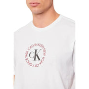 Blanc Calvin Klein Jeans hommes t-shirt présentant un logo circulaire rouge avec les initiales ck et du texte sur le devant