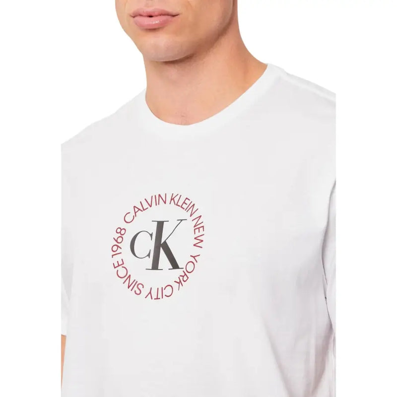Blanc Calvin Klein Jeans hommes t-shirt présentant un logo circulaire rouge avec les initiales ck et du texte sur le devant