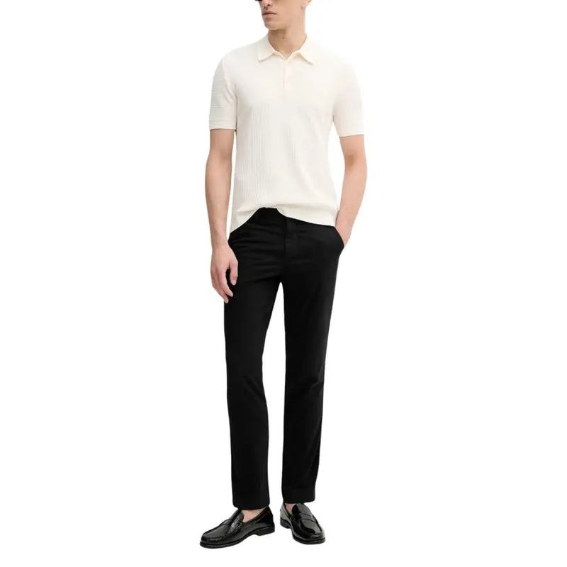 Calvin Klein Jeans Pantalon pour homme porté avec un polo en maille côtelée couleur crème, à col classique et manches courtes.