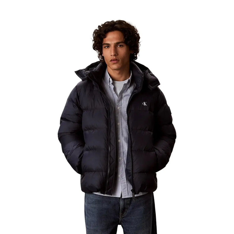 Calvin Klein Jeans Doudoune noire pour homme, matelassée, avec logo blanc sur la poitrine gauche (vue de face).