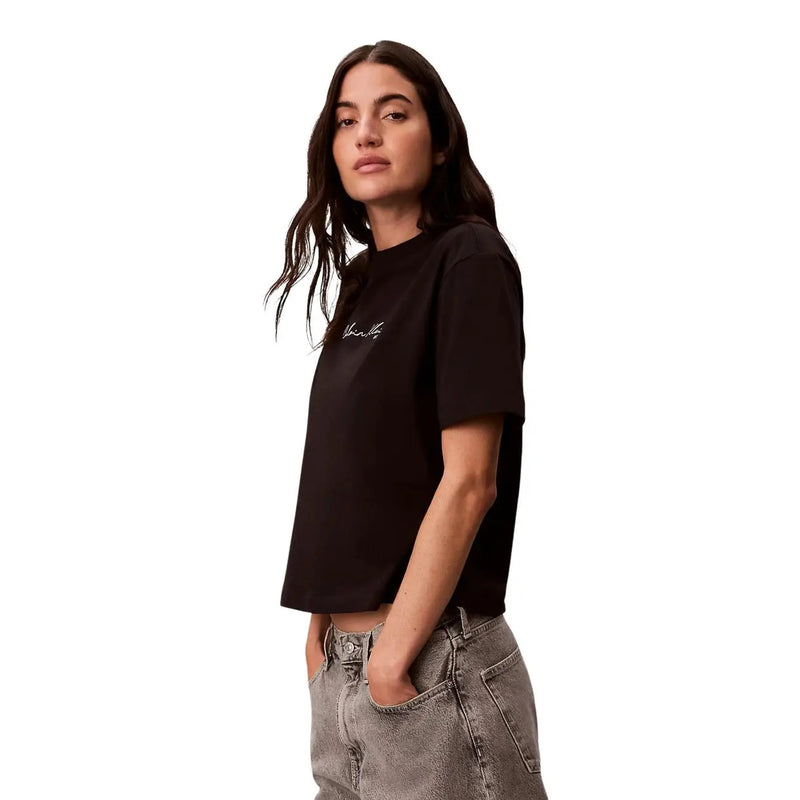 Calvin Klein Jeans T-shirt noir à manches courtes en coton pour femme, orné d'un discret logo blanc en écriture cursive sur la poitrine.