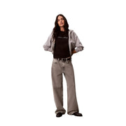 Jean en denim gris à jambes larges, délavé et légèrement texturé, associé à un t-shirt noir en coton à col rond Calvin Klein Jeans pour femme.