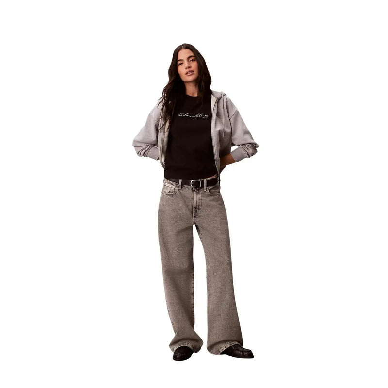 Jean en denim gris à jambes larges, délavé et légèrement texturé, associé à un t-shirt noir en coton à col rond Calvin Klein Jeans pour femme.