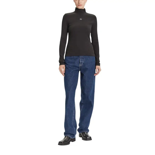 Woman wearing Calvin Klein Jeans black long turtleneck knitwear with blue jeans and black boots