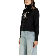 Women wearing black Calvin Klein turtleneck sweater with large CK logo and light wash jeans