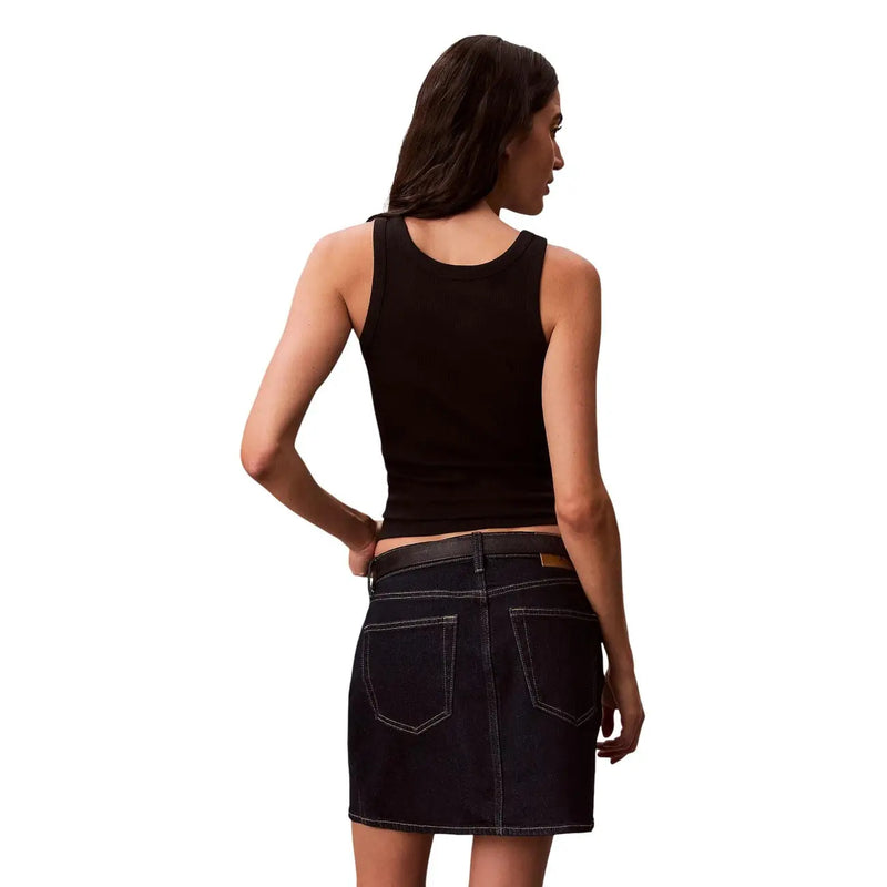 Jupe courte en jean noir Calvin Klein pour femme, avec surpiqûres blanches et passant de ceinture en cuir marron, à porter avec un haut sans manches. top