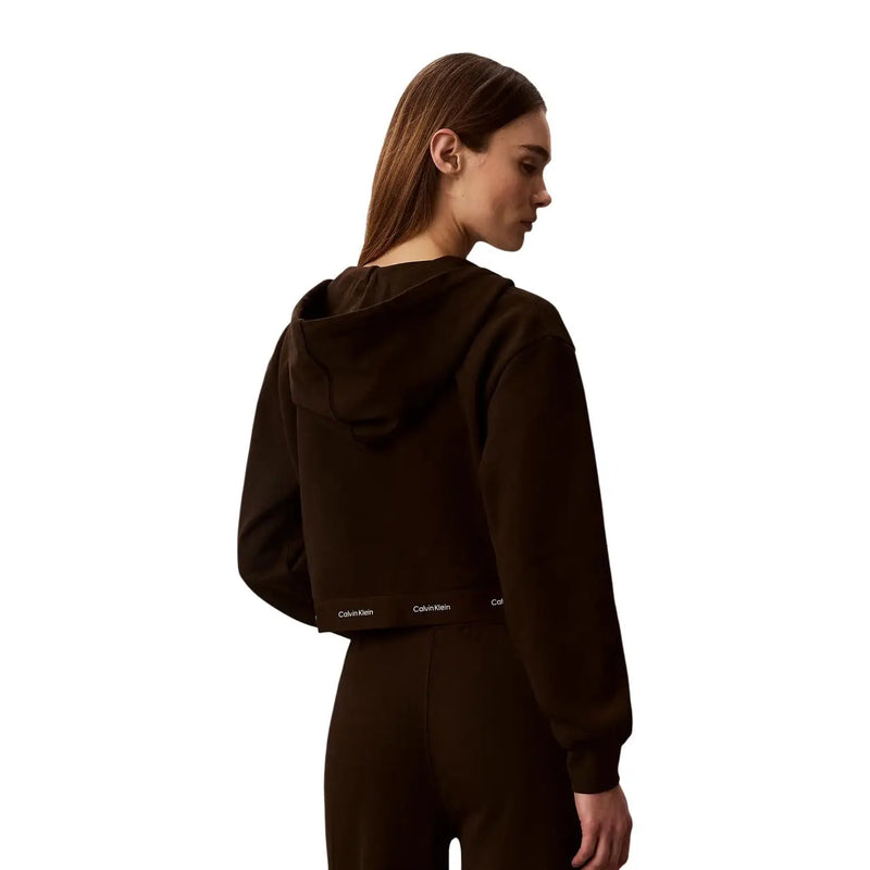 Back side of a dark brown cotton cropped hoodie with a subtle white calvin klein logo on the lower back