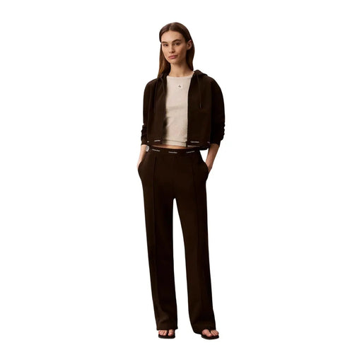 Un noir élégant Calvin Klein Sweat à capuche en coton avec logo discret, porté avec un pantalon à jambes larges pour femme