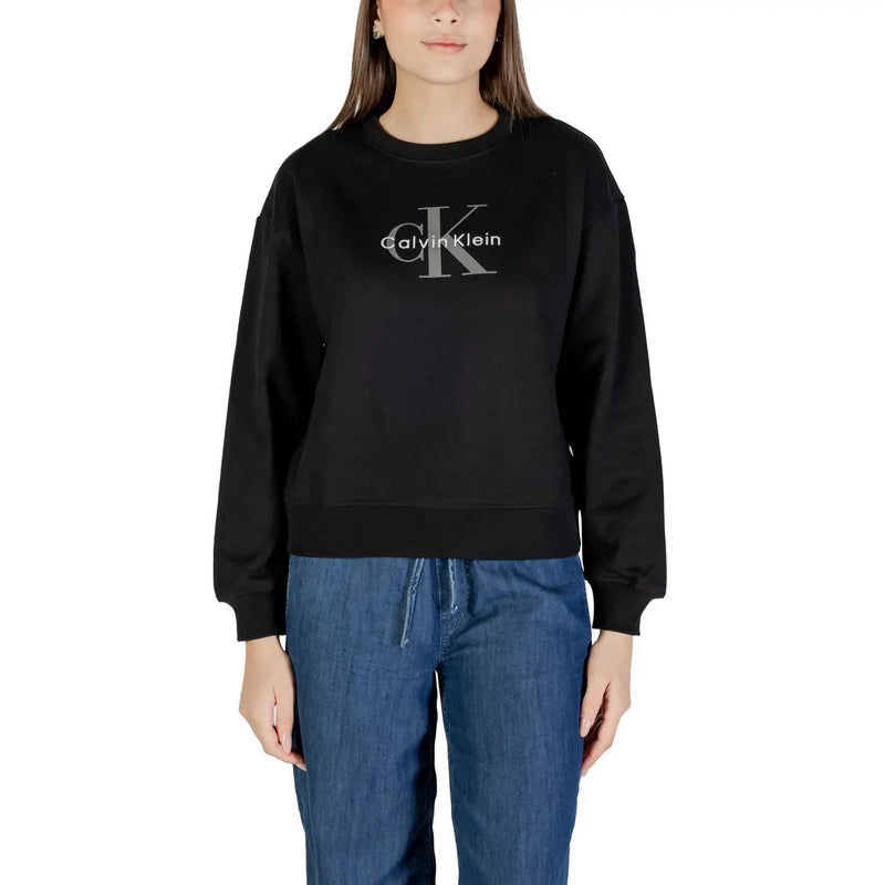 Woman wearing a black Calvin Klein long-sleeved sweatshirt and blue denim drawstring pants