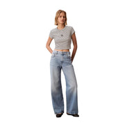 Un jean en denim clair à jambes larges et coupe classique cinq poches, associé à un t-shirt rayé noir à col rond Calvin Klein pour femme. top