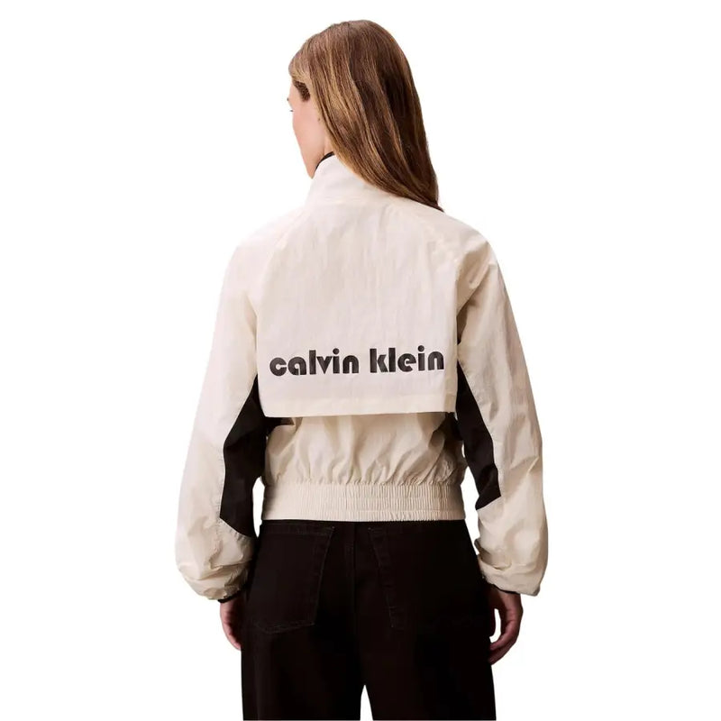 Back of a cream-colored calvin klein bomber jacket with black contrast panels and bold logo for women
