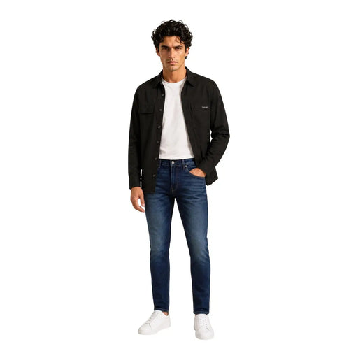Chemise longue Calvin Klein pour homme en mélange de coton noir, portée avec un jean slim bleu foncé à délavage subtil aux genoux.
