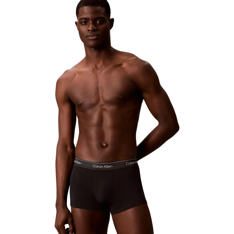 Black calvin klein cotton trunks with a gray waistband featuring the brand logo in white lettering in a 3 pack