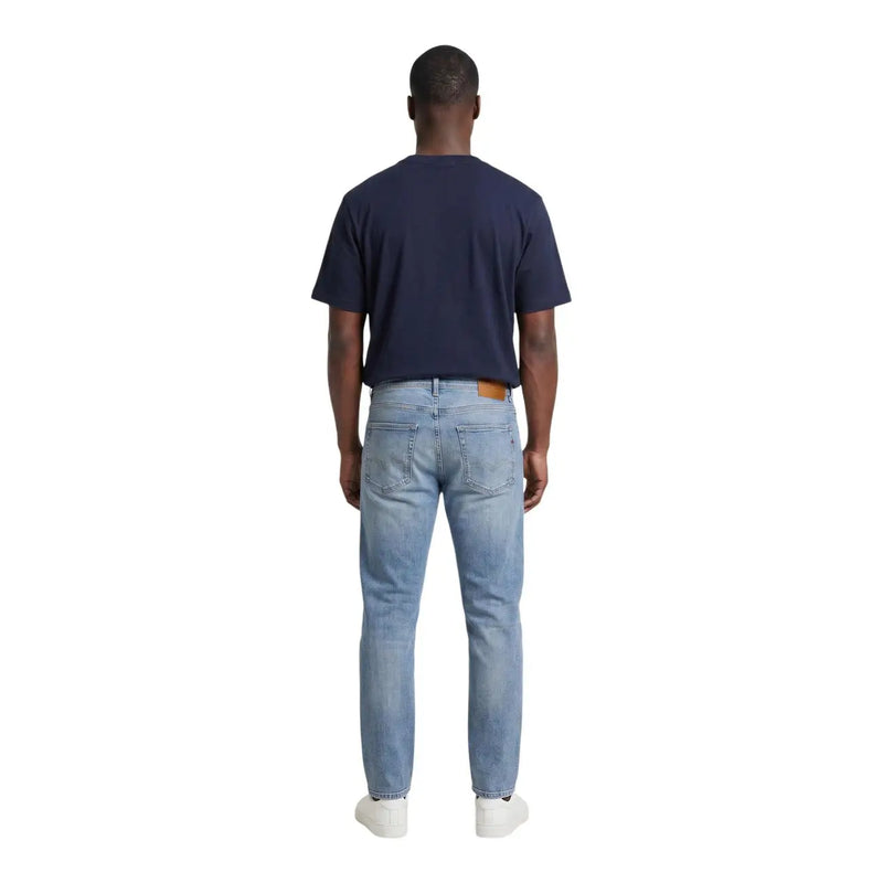 Jean en denim clair délavé, coupe classique cinq poches et empiècement en cuir marron à l'arrière de la ceinture, pour un style décontracté.