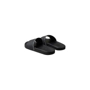 Sandales mules Calvin Klein noires pour homme, à bout ouvert, en polyuréthane, au design minimaliste et au logo blanc discret.