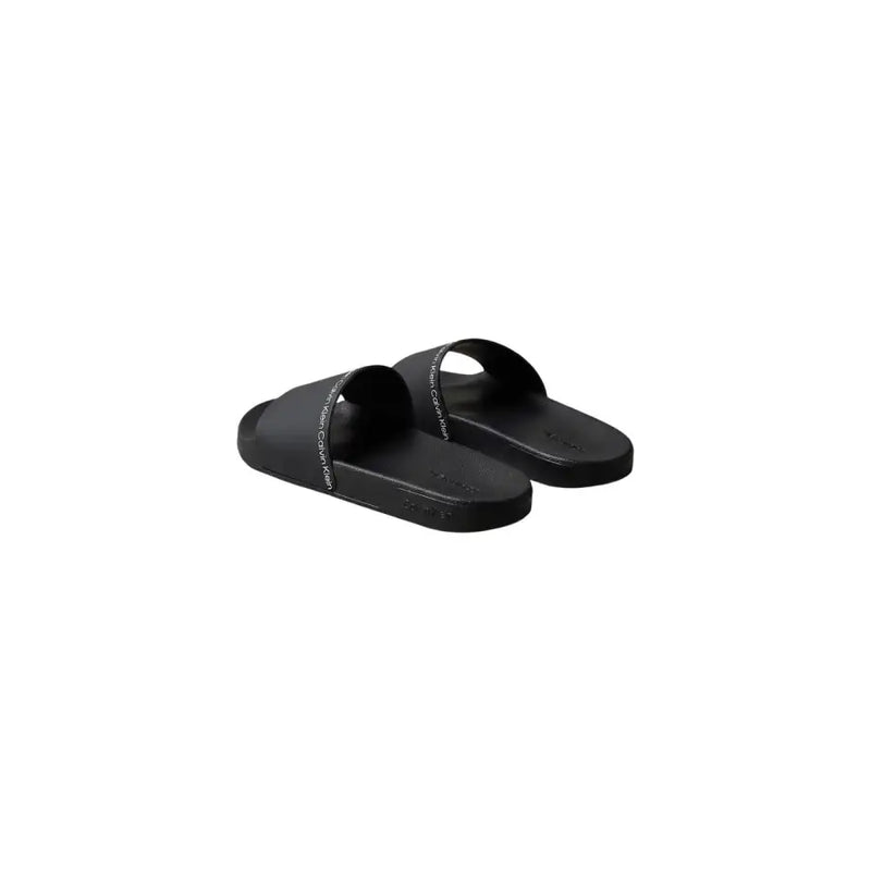 Sandales mules Calvin Klein noires pour homme, à bout ouvert, en polyuréthane, au design minimaliste et au logo blanc discret.