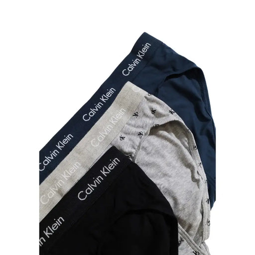 Three pairs of men’s briefs in navy blue, grey, and black from Calvin Klein Underwear