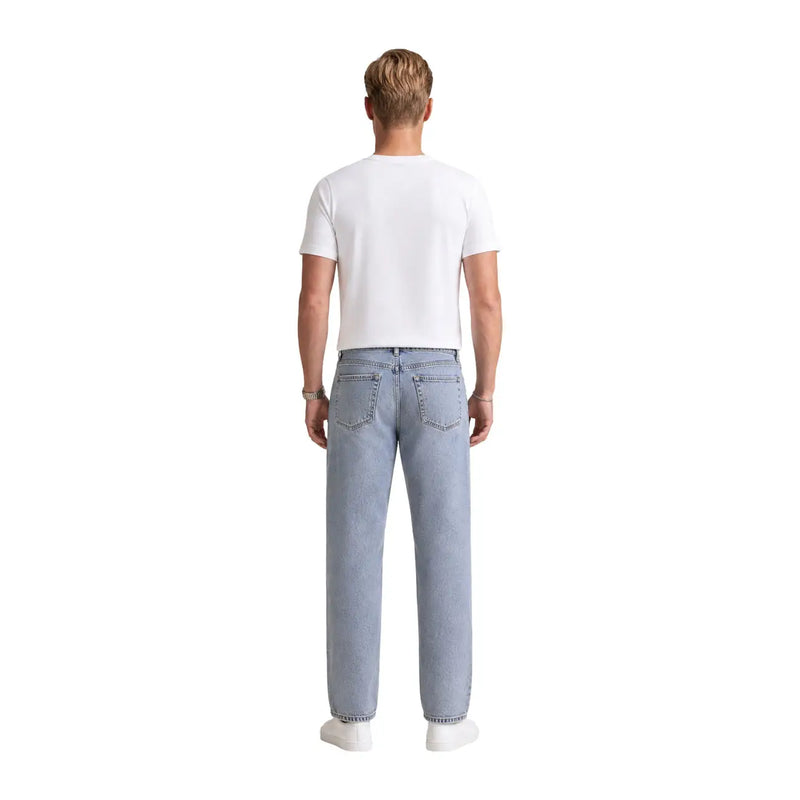 Jean en denim clair à coupe droite et poches arrière classiques, associé à un t-shirt blanc en coton à motif Calvin Klein pour homme.
