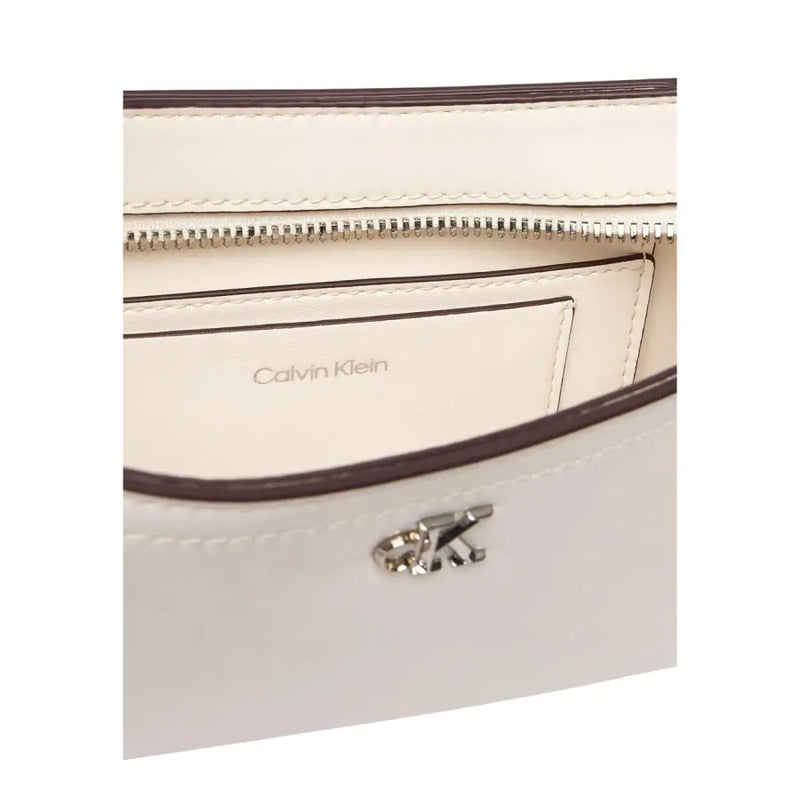 Cream-colored leather Calvin Klein crossbody bag with dark brown trim and silver-tone CK logo clasp for women